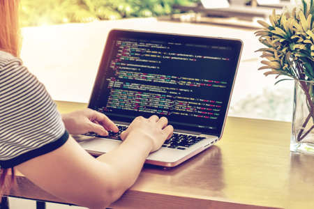Close-up of programmer's hands working on source codes over a laptop on a sunny day.