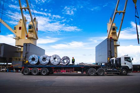 Truck receive steel coils alongside large cargo ship at portの写真素材