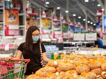 New normal, young asian women wearing mask shopping in the store during coronavirus pandemic crisis.の写真素材