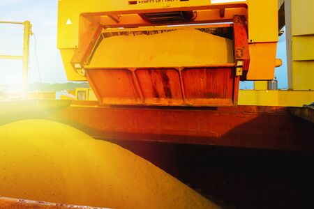 Raw sugar bulk loaded into large vessel hole by rotainer for export. Sugar bulk products transport and handling. Agro-industry concept.の写真素材