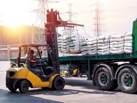 Forklift unloading and loading sugar bags from truck at warehouse dock. Forklift stacking up sugar bag inside warehouse, sugar warehouse operation. Agriculture product storing and logistics for import and export.の写真素材