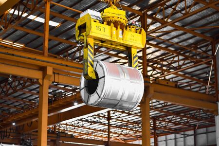 Overhead crane lift up steel coil with tong in wearhouse. Steel coils handling equipment. Steel...
