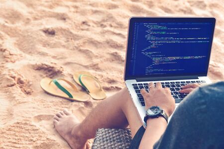 A programmer typing source codes at the beach in a relaxing working environment. Studying, Working, Technology, Freelance Work Concept.の写真素材