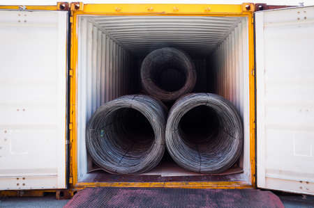 Coils of steel wire rod stuffed inside container. Container open for unloading steel wire rod.