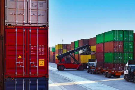 Container yard operation activity, reach stacker load container onto trailers. Container terminal, port operation, and logistics.の写真素材