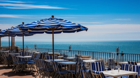 View of the sea from the terrace of a restaurant with blue striped parasolの素材
