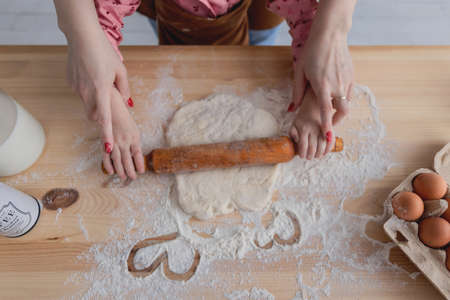 mother and daughter in the kitchen prepare food from flour, and draw hearts on flour
