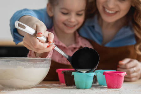 mom and daughter in the kitchen have fun and cook food from flour, milk and eggs