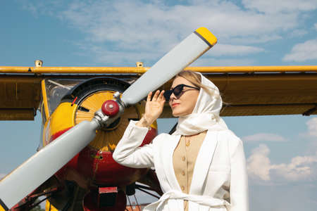 woman in black glasses and white clothes on a background of an airplane in summerの写真素材