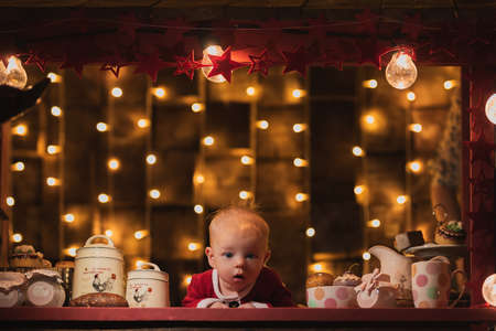 a little boy in a santa claus costume lies and holds the hand of his parents