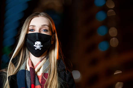 a girl in a black mask on her face walks in the night cityの写真素材