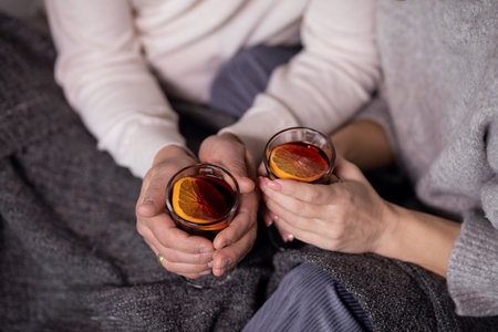 female and male hands holding glasses of mulled wineの写真素材