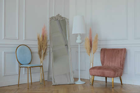 blue and pink chairs and a large mirror on a white wall backgroundの写真素材