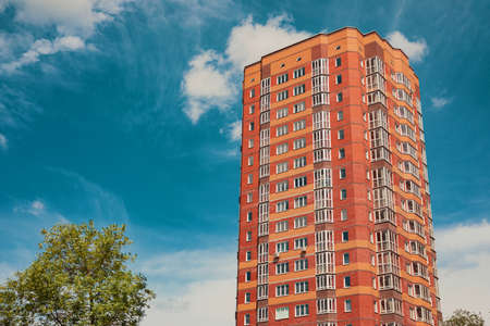 brick building from orange bricks close-up under blue sky and next to the parkの写真素材
