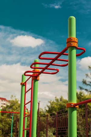 green and red horizontal bars on a playground in the summerの写真素材