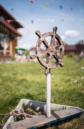 children's wooden steering wheel from the ship on the green grassの写真素材