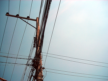 Chaotic wire on electric posts and blue sky backgroundの写真素材