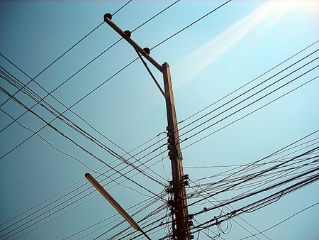 Chaotic wire on electric posts and blue sky backgroundの写真素材