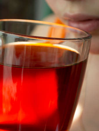 a photo of a girl drinking black tea from a transparent large mug. Close upの写真素材