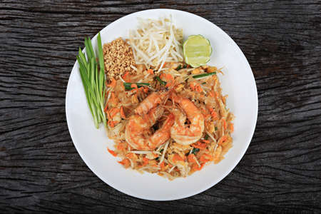 An overhead photo of a Shrimp Pad Thai, traditional Thai dish with stir fried rice noodles, shot from above on a rustic textureの写真素材