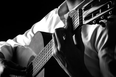 Man playing acoustic guitar on dark background, closeup. Black and whiteの写真素材