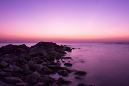 Long exposure seascape with rocks in the foreground and purple sky