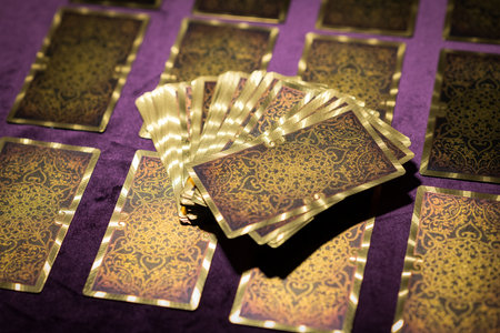 From above set of tarot card with golden ornament on reverse side placed on purple tableの写真素材