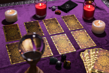 High angle deck of ornamental tarot cards and burning candles placed on table with purple fabricの写真素材