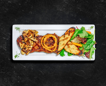 New York Striploin Steak. Healthy food. Grilled steak served with two sides, garlic toast, mushrooms and tossed salad. Chalked background. Top viewの写真素材