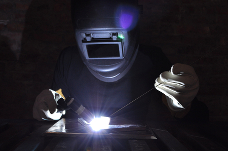 welder welds metal using tig with black backgroundの写真素材