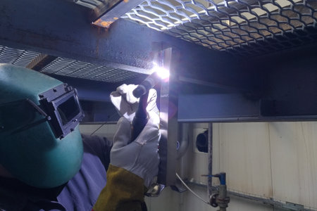 Welder at work in a factory using an arc welding machine