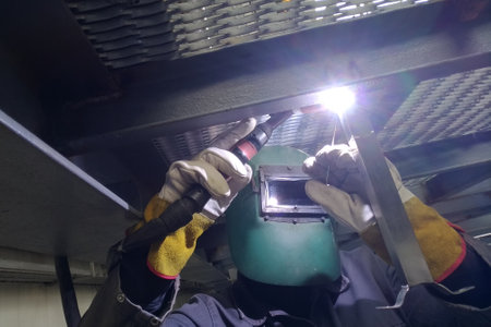 TIG welder joining metal with protective helmet and gloves
