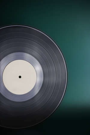Classic vinyl record close-up on a green background, obsolete data storage, music