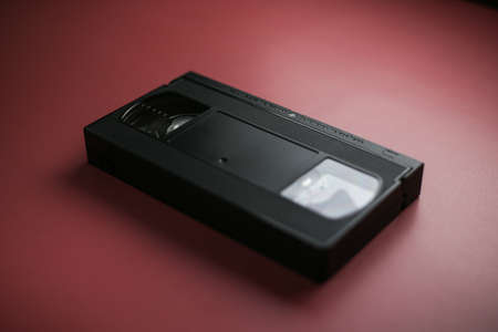 Close-up classic cassette tape on a red-burgundy background, outdated data storageの写真素材