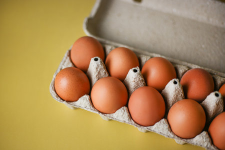 Brown eggs in eco packaging made from recycled materials on an isolated light yellow background