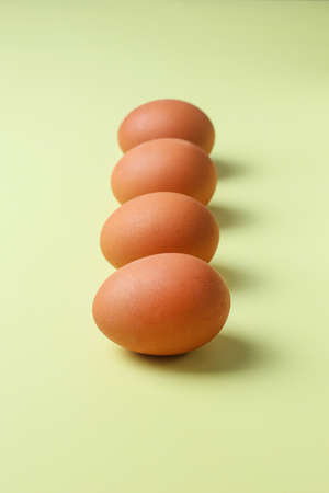 Brown eggs on a light yellow isolated backgroundの写真素材