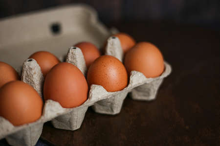 Brown eggs in eco-packaging from recycled materials on a dark wooden background