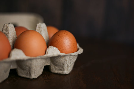 Brown eggs in eco-packaging from recycled materials on a dark wooden backgroundの写真素材