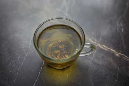 Illuminated brewed herbal green tea in a transparent cup on a dark backgroundの素材 [FY310187417529]