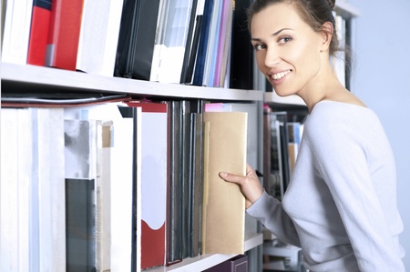 Young women stands in a modern office near bookshelf の写真素材