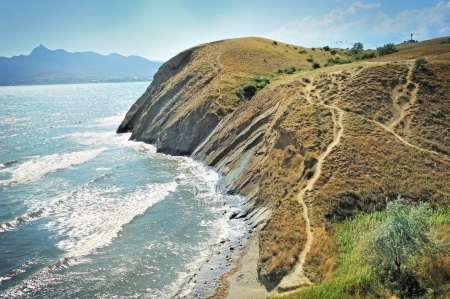Steep cliff at the edge of the sea, against the backdrop of the Crimean Mountains の写真素材