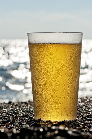 Plastic cup of beer standing on the sand by the sea.の写真素材