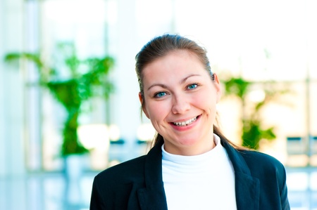 Portrait of a smiling girl on the background of the manager de-focus office interiorの写真素材