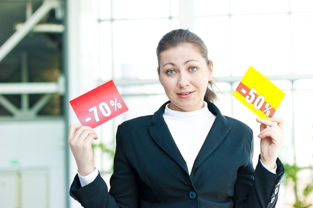Brunette girl in confusion holds two tablets with discountsの写真素材