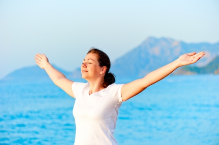 Woman with arms outstretched enjoying the sun by the seaの写真素材