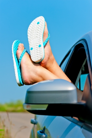 female legs dangling from the open car window in the shalesの写真素材
