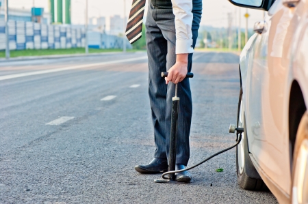  man in a business suit pumps hand pump wheel of a carの写真素材