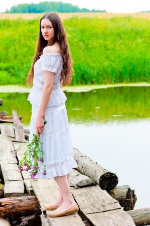 girl standing on the bridge over the river with a bouquetの写真素材