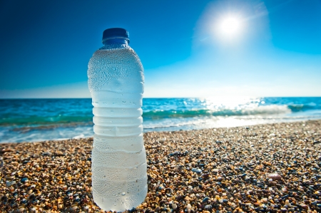 bottle of cold fresh water on the pebble beachの写真素材
