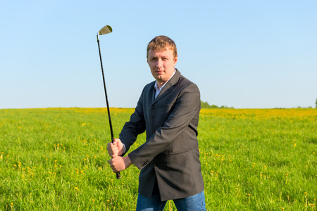 man in a business suit holding a golf clubの写真素材